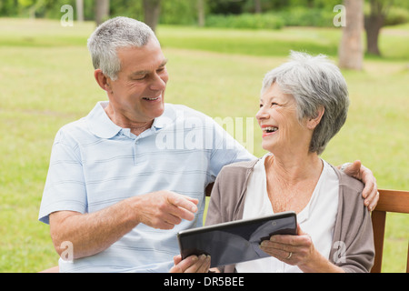 Fröhliche älteres Paar mit digital-Tablette auf Bank im park Stockfoto
