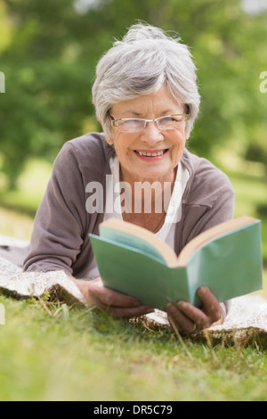 Ältere Frau liest ein Buch im park Stockfoto