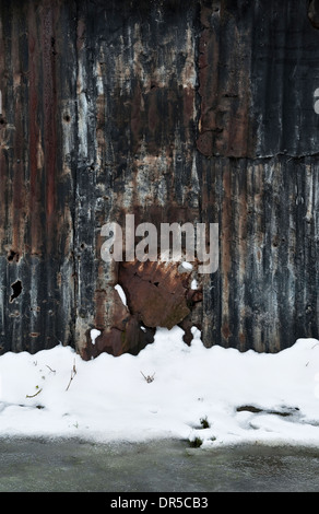 Schnee, der eine alte und rostende Wellblechscheune auf einem Bauernhof im Winter in Großbritannien bedeckt Stockfoto