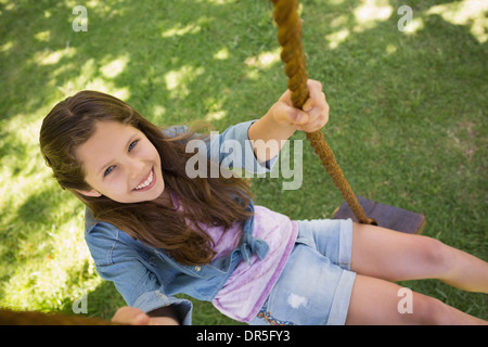 Niedliche kleine junge Mädchen sitzen auf Schaukel Stockfoto