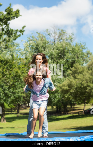 Glückliches Mädchen und Mutter hoch springen auf dem Trampolin im park Stockfoto