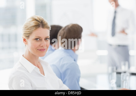 Geschäftsfrau, die lächelnd in die Kamera während eines Meetings Stockfoto