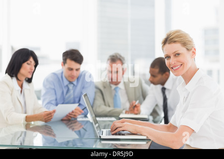 Geschäftsfrau mit ihrem Laptop während eines Treffens in die Kamera Lächeln Stockfoto