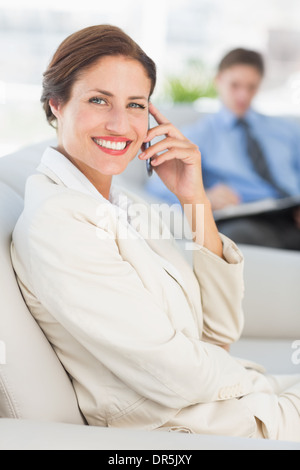 Fröhliche Geschäftsfrau auf dem Telefon auf couch Stockfoto