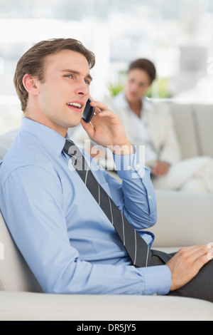 Fröhliche Geschäftsmann auf dem Telefon auf sofa Stockfoto