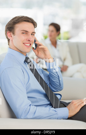 Lächelnde Geschäftsmann auf dem Telefon auf sofa Stockfoto