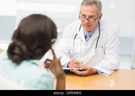 Reife Arzt anhören seiner Patienten und Notizen Stockfoto