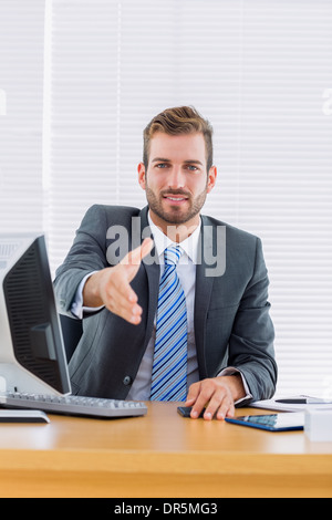 Geschäftsmann mit einem Handschlag am Schreibtisch Stockfoto