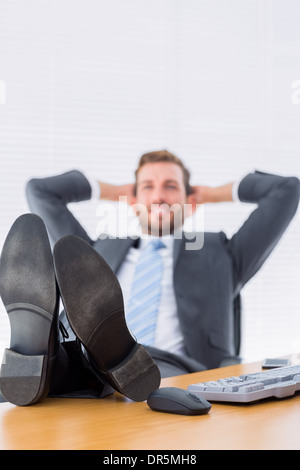 Entspannt sitzen mit den Beinen am Schreibtisch Geschäftsmann Stockfoto