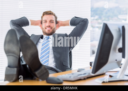 Entspannt sitzen mit den Beinen am Schreibtisch Geschäftsmann Stockfoto