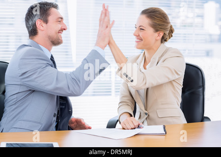 Elegant gekleidet Kolleginnen und Kollegen, die so hohe fünf im Business-meeting Stockfoto