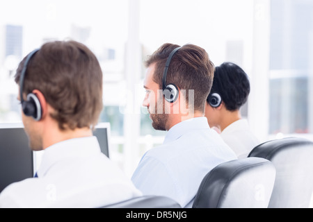 Geschäftskollegen mit Headsets in einer Reihe Stockfoto