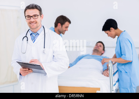 Arzt hält Berichte mit Patient und Chirurg im Hintergrund Stockfoto