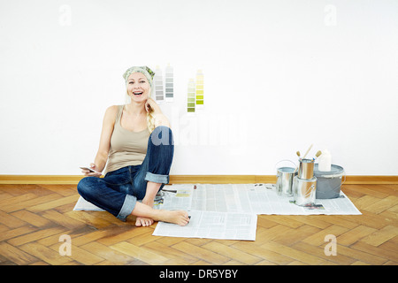 Frau sitzt auf Parkett, Farbmuster an der Wand, München, Bayern, Deutschland Stockfoto