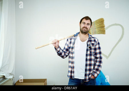 Der Mensch steht mit Besen gegen Herzform an Wand, München, Bayern, Deutschland Stockfoto