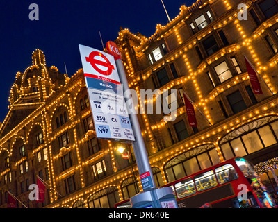 Das Kaufhaus Harrods mit eigener Bushaltestelle und vorbeifahrenden roten London bus Knightsbridge London UK Stockfoto