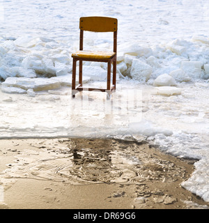 eingefrorene Stuhl am Rand des Eisloch im zugefrorenen See im winter Stockfoto