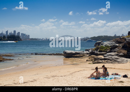 Milch-Strand mit drei Frauen, entspannend, Sydney Harbour Bridge und die Skyline der Stadt im Hintergrund Sydney New South Wales NSW Australia Stockfoto