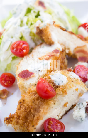 Salat mit geschnittenen panierte Huhn, Speck, Tomaten und ein Blauschimmelkäse Buttermilch Kräuterdressing serviert mit einem Eisberg-Keil Stockfoto