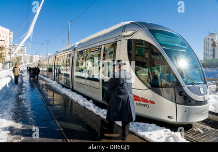 Jerusalem, Israel. Ein Ultra-orthodoxer jüdischer Mann geht eine nicht-operative Stadtbahn, im Schnee stecken. Stockfoto