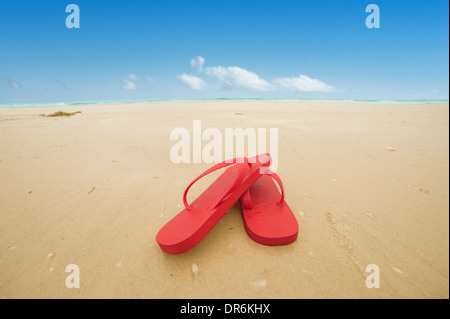 Roten Flip-Flops auf den Strandsand. Konzept der Sommerferien Stockfoto