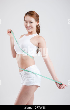 eine gesund aussehende Frau mit Maßband um den Körper Stockfoto