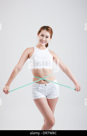 eine gesund aussehende Frau mit Maßband um den Körper Stockfoto