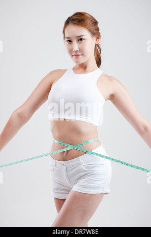 eine gesund aussehende Frau mit Maßband um den Körper Stockfoto