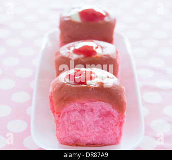 Bunten rosa Kokos Guave süße Brötchen mit Frischkäse-Vanillepudding gefüllt und garniert mit Guave-Saft-Konzentrat Stockfoto