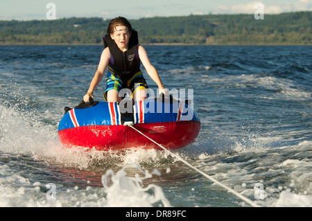 Boy freudig und furchtlos reitet Innenrohr auf See auf Ein sonniger Sommertag Stockfoto