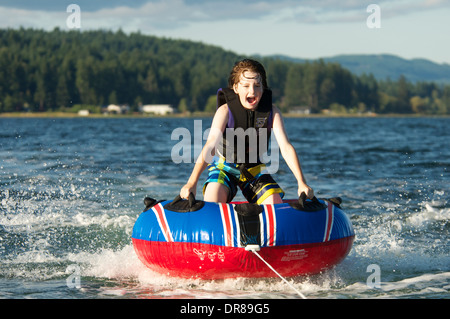 Boy freudig und furchtlos reitet Innenrohr auf See auf Ein sonniger Sommertag Stockfoto