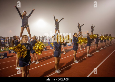 Cheerleader unterhalten die Zuschauer bei einem Fußballspiel Gymnasium Nacht in San Juan Capistrano, Kalifornien, Initialen der Name der Schule zu halten. Beachten Sie die "Flyer" auf den Schultern der anderen Cheerleader. Stockfoto