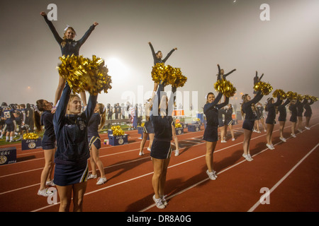 Cheerleader unterhalten die Zuschauer bei einem Fußballspiel Gymnasium Nacht in San Juan Capistrano, Kalifornien, Initialen der Name der Schule zu halten. Beachten Sie die "Flyer" auf den Schultern der anderen Cheerleader. Stockfoto