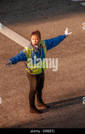 Ein asiatisch-amerikanische Polizeibeamter regelt den Verkehr auf dem Campus der University of California in Irvine. Beachten Sie die hellen Morgen Licht- und Sichtverhältnissen Sicherheitskleidung. Stockfoto