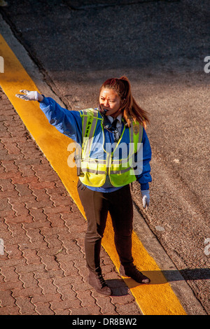 Ein asiatisch-amerikanische Polizeibeamter regelt den Verkehr auf dem Campus der University of California in Irvine. Beachten Sie die hellen Morgen Licht- und Sichtverhältnissen Sicherheitskleidung. Stockfoto