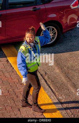 Ein asiatisch-amerikanische Polizeibeamter regelt den Verkehr auf dem Campus der University of California in Irvine. Beachten Sie die hellen Morgen Licht- und Sichtverhältnissen Sicherheitskleidung. Stockfoto