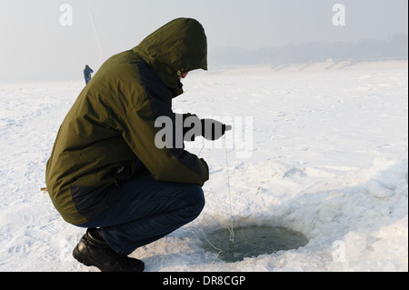 Eisangeln Sie auf dem gefrorenen Fluss Songhua-Fluss. Harbin, Provinz Heilongjiang, China Stockfoto