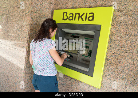 Junge Frau, die Bankia ATM, Spanien Euro entziehen Stockfoto