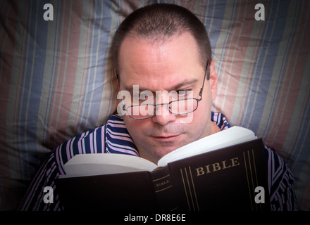 Mann liest die Bibel im Bett Stockfoto