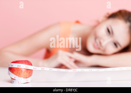 eine Frau und einen Apfel umhüllt mit Maßband Stockfoto