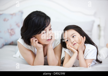 eine Frau und Enkelin auf einem Bett liegend Stockfoto