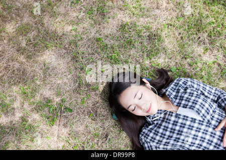 eine Frau liegt auf dem Rasen mit geschlossenen Augen Stockfoto