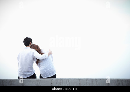 ein Mann und eine Frau sitzen auf einer Kante Stockfoto