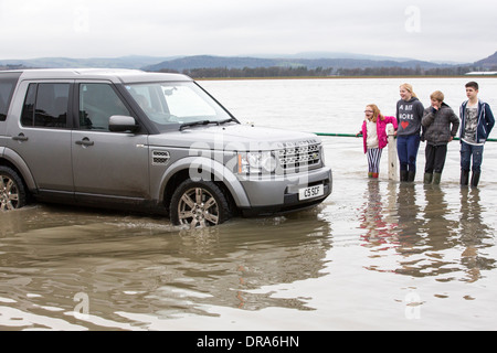 Eine Autofahrer fährt durch Hochwasser auf der Straße bei Storth an der Mündung der Kent in Cumbria, UK, während der Januar 2014 Stürme Stockfoto