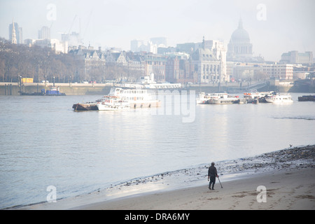 Mann zu Fuß entlang der Flussufer Strand bei Ebbe auf der Themse mit seinem Metalldetektor Suche entlang der South Bank. Stockfoto