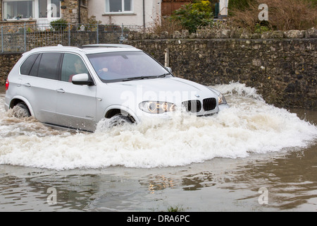 Eine Autofahrer fährt durch Hochwasser auf der Straße bei Storth an der Mündung der Kent in Cumbria, UK, während der Januar 2014 Stürme Stockfoto