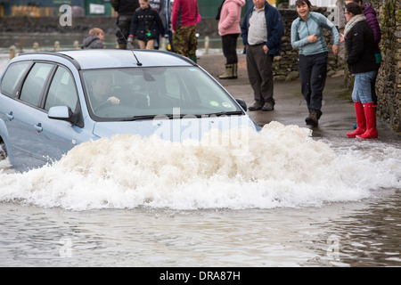 Eine Autofahrer fährt durch Hochwasser auf der Straße bei Storth an der Mündung der Kent in Cumbria, UK, während der Januar 2014 Stürme Stockfoto