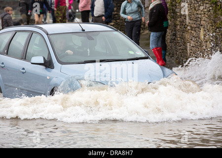 Eine Autofahrer fährt durch Hochwasser auf der Straße bei Storth an der Mündung der Kent in Cumbria, UK, während der Januar 2014 Stürme Stockfoto