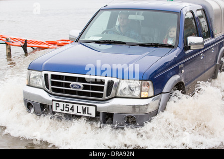 Eine Autofahrer fährt durch Hochwasser auf der Straße bei Storth an der Mündung der Kent in Cumbria, UK, während der Januar 2014 Stürme Stockfoto