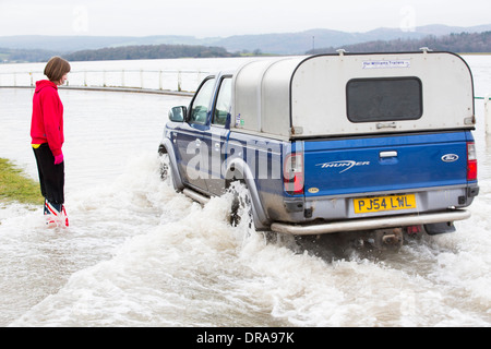 Eine Autofahrer fährt durch Hochwasser auf der Straße bei Storth an der Mündung der Kent in Cumbria, UK, während der Januar 2014 Stürme Stockfoto